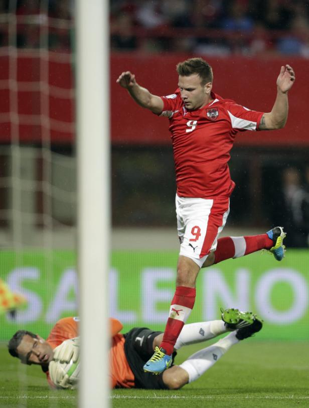 Ein österreichischer Fußballspieler springt über einen am Boden liegenden Torwart.