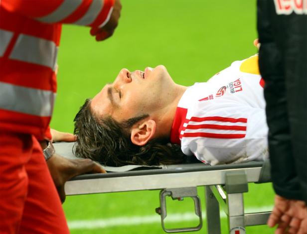Ein verletzter Fußballspieler wird auf einer Trage vom Spielfeld gebracht.