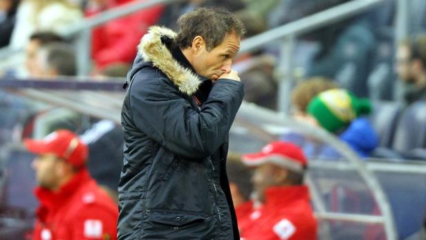 Ein Mann mit Winterjacke steht nachdenklich am Spielfeldrand.