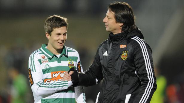 Ein Fußballspieler und sein Trainer schütteln sich die Hände.