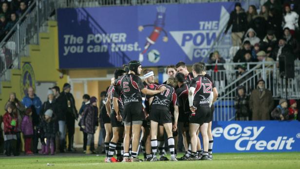 Eine Rugby-Mannschaft steht im Kreis auf dem Spielfeld.