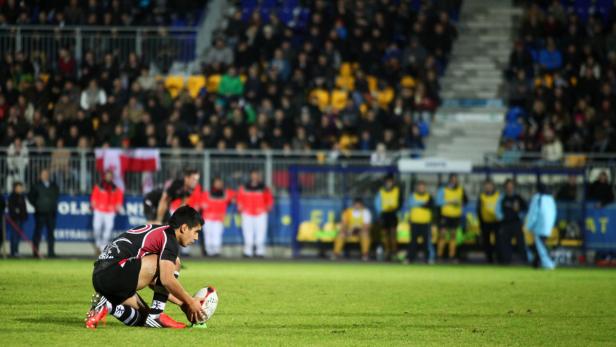 Ein Rugby-Spieler bereitet sich auf einem Rasenfeld vor, den Ball zu kicken.