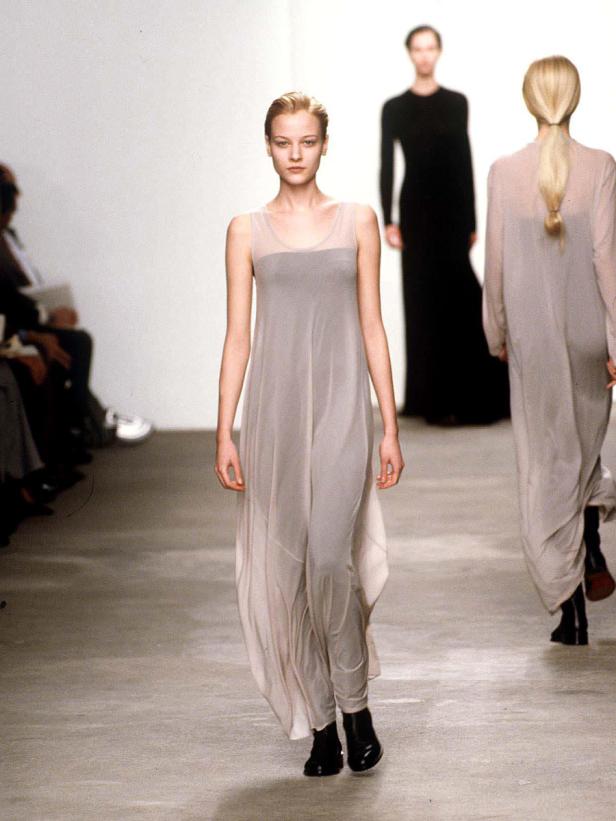 Eine Frau in einem langen, hellen Kleid auf einem Laufsteg.