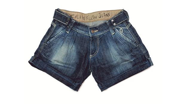 Eine blaue Jeansshorts der Marke Calvin Klein liegt auf einem weißen Hintergrund.