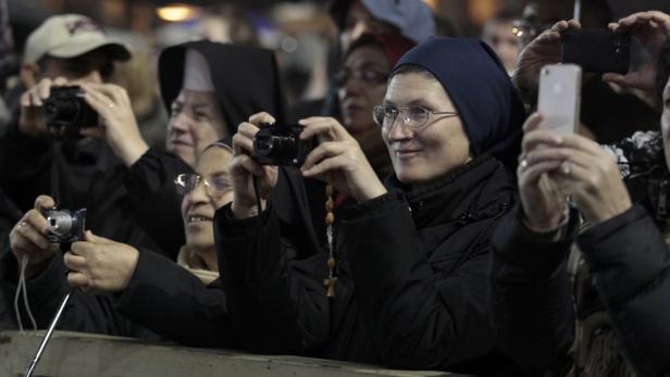 Eine Gruppe von Nonnen und anderen Personen fotografiert mit Kameras und Handys.