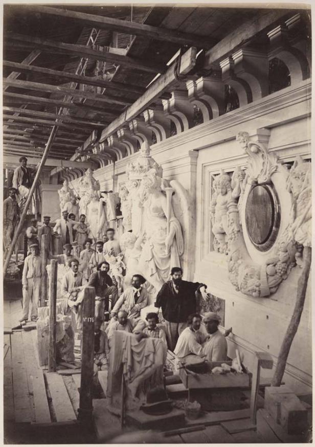 Eine Gruppe von Bildhauern arbeitet an Statuen in einer Werkstatt.