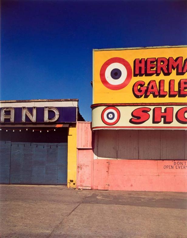 Ein farbenfrohes Gebäude mit der Aufschrift „Herma Gallery Shop“ unter blauem Himmel.