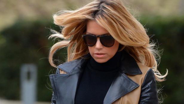 Eine Frau mit Sonnenbrille und blonden Haaren trägt eine Lederjacke.