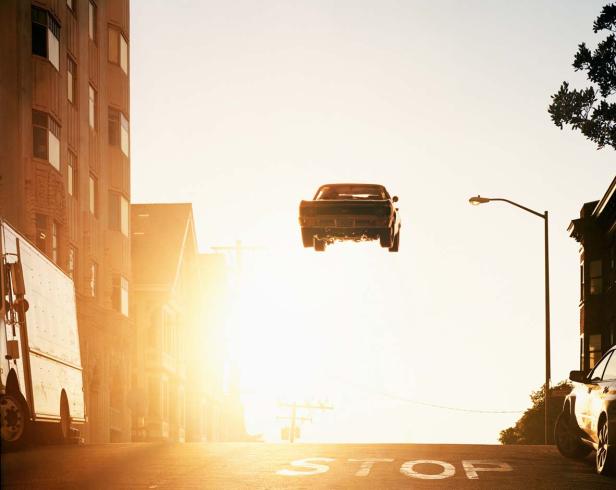 Ein Auto springt über eine Straße mit einem Stoppschild in einer Stadt.