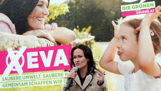 Eine Frau spricht vor einem Wahlplakat der Grünen, auf dem eine weitere Frau und ein Kind zu sehen sind.