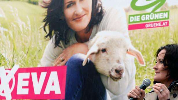 Eva Glawischnig von den Grünen hält eine Rede vor einem Wahlplakat mit einem Lamm.