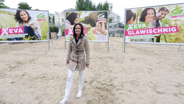 Eva Glawischnig steht vor Wahlplakaten der Grünen am Strand.