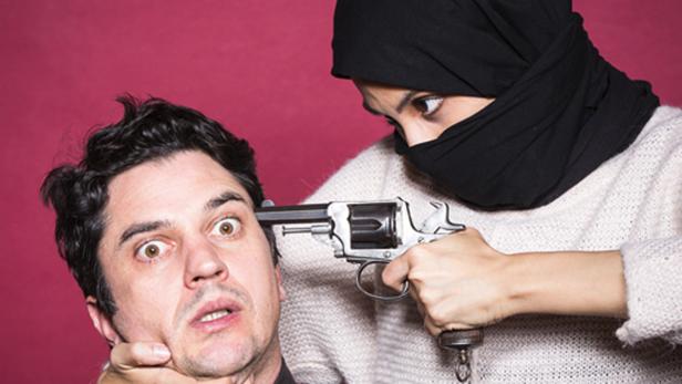 Eine Frau mit Nikab bedroht einen Mann mit einer Pistole.