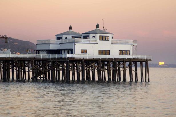 Das Malibu Pier mit einem zweistöckigen Gebäude am Ende des Piers bei Sonnenuntergang.