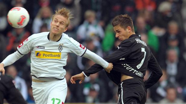 Ein Fußballspieler zieht am Trikot seines Gegners, während ein Ball in der Luft ist.