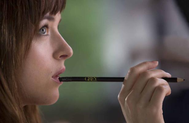 Dakota Johnson hält einen Bleistift der Marke „Grey“ im Mund.