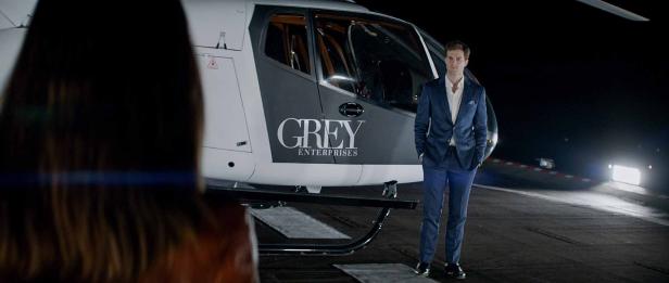 Jamie Dornan steht vor einem Hubschrauber von Grey Enterprises.