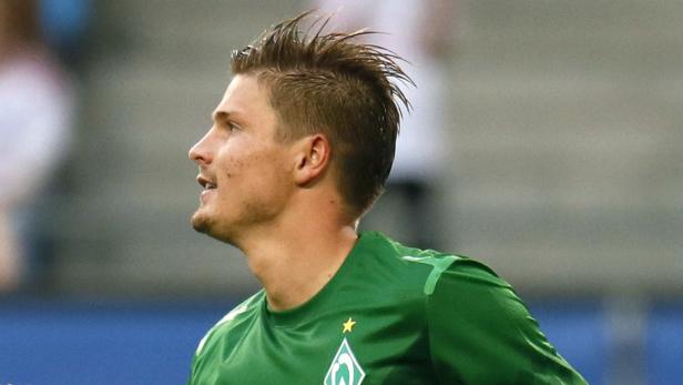 Ein Mann im grünen Trikot von Werder Bremen blickt nach oben.