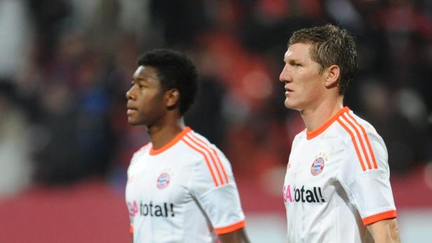 David Alaba und Bastian Schweinsteiger, zwei Fußballspieler des FC Bayern München, stehen nebeneinander.