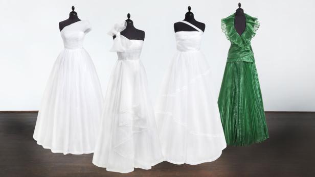 Vier Kleider, davon drei weiße Brautkleider und ein grünes Abendkleid, auf Schneiderpuppen.