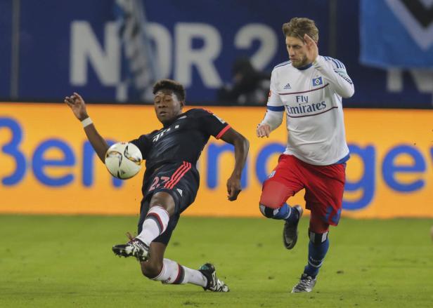 David Alaba (FC Bayern) grätscht im Zweikampf gegen einen Spieler des Hamburger SV.
