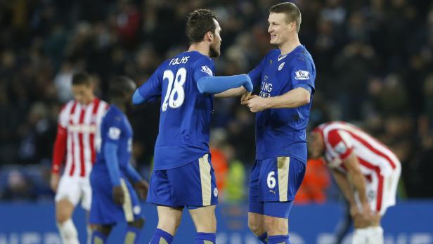 Zwei Fußballspieler in blauen Trikots geben sich die Hand.