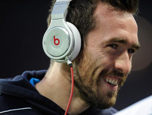 Ein lächelnder Mann mit Bart trägt silberne Beats-Kopfhörer.