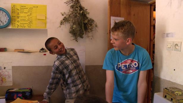 Zwei Jungen unterhalten sich in einem Klassenzimmer.