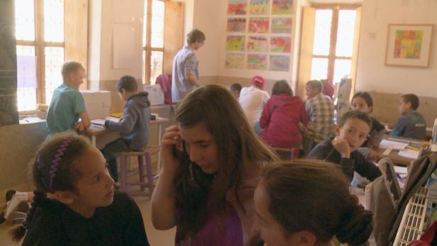 Eine Schulklasse mit Schülern und einem Lehrer in einem hellen Raum.