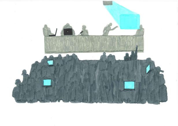 Eine Gruppe von Menschen sitzt an einem Tisch vor einer Menschenmenge mit Bildschirmen.