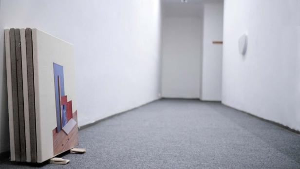 Mehrere Leinwände mit abstrakten Darstellungen stehen in einem leeren Raum.