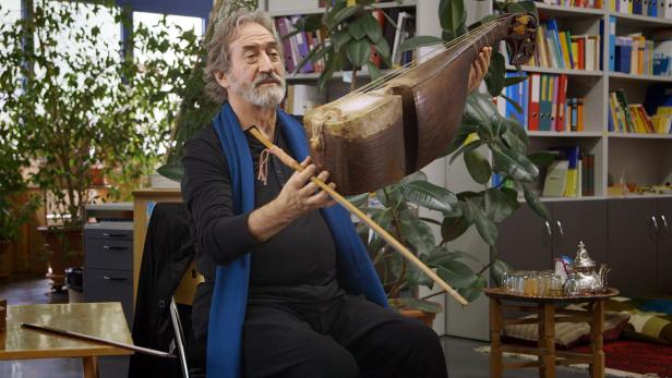 Ein Mann mit Bart spielt ein Saiteninstrument mit einem Bogen.