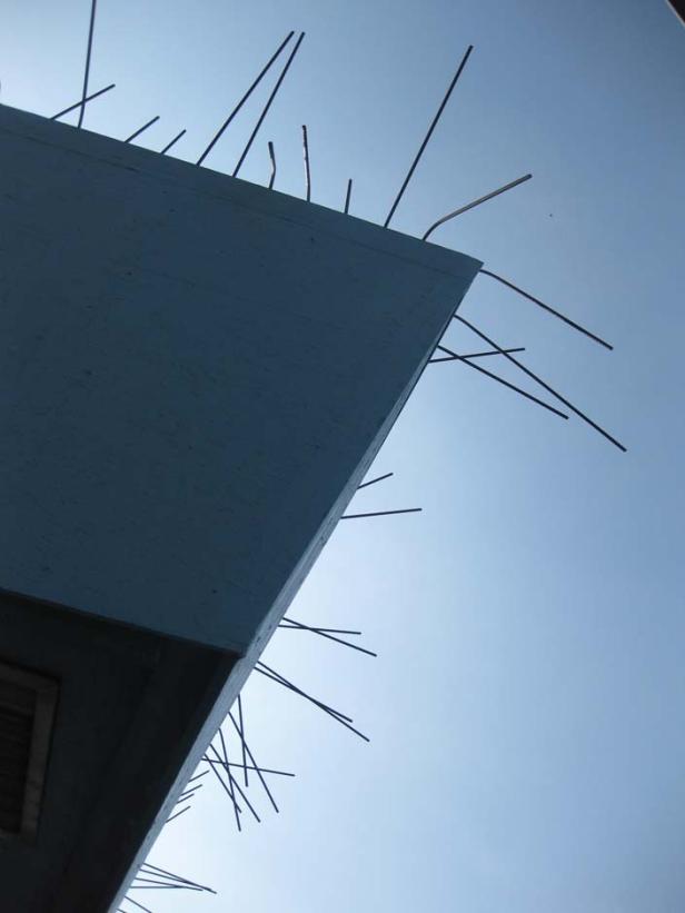 Ein Gebäude mit Vogelabwehrspitzen gegen einen blauen Himmel.