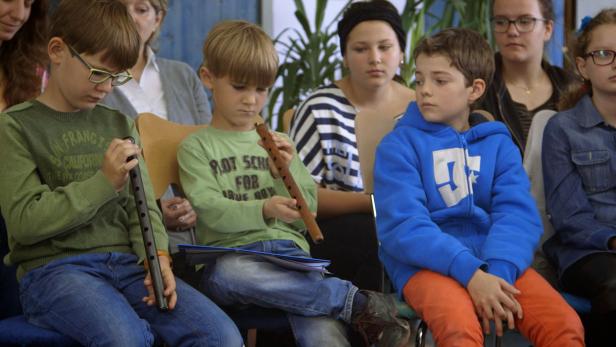 Eine Gruppe von Kindern sitzt mit Blockflöten in einem Raum.