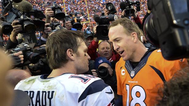 Tom Brady und Peyton Manning umringt von Fotografen.