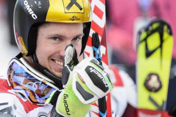 Ein lächelnder Skirennläufer mit Helm und Skibrille gibt ein Zeichen.