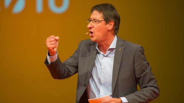 Ein Mann mit Brille gestikuliert während einer Rede mit erhobener Faust.