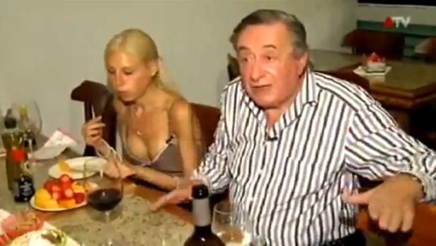 Ein Mann und eine Frau sitzen an einem Tisch mit Obst und Wein.