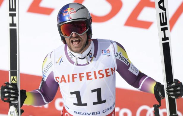 Ein Skirennläufer jubelt mit Skiern in der Hand.