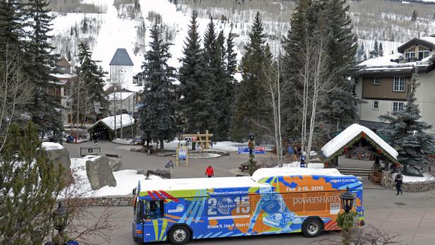 Ein Bus mit Werbung für die Skiweltmeisterschaften 2015 in Vail/Beaver Creek vor einer verschneiten Bergkulisse.