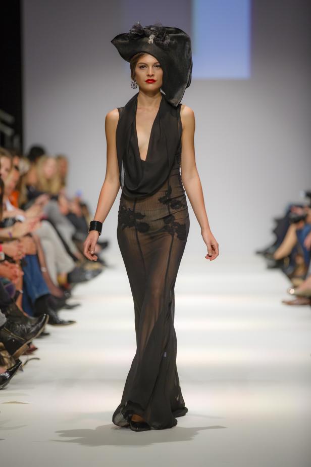 Eine Frau mit Hut und schwarzem Kleid auf dem Laufsteg.