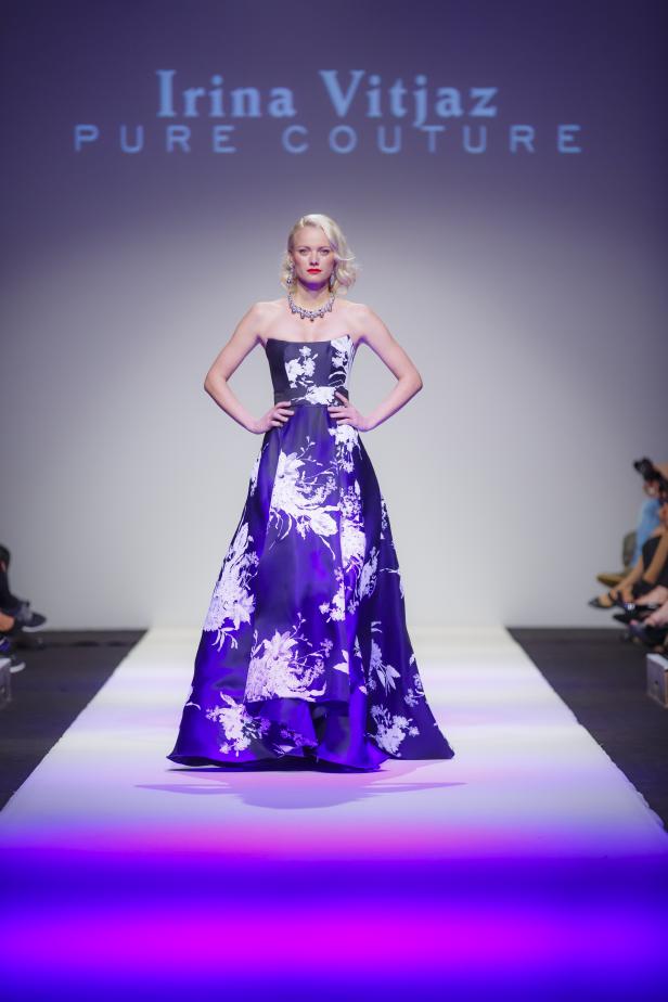 Eine blonde Frau präsentiert ein blaues, blumengemustertes Abendkleid auf dem Laufsteg.