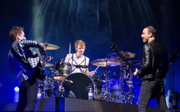Eine Band spielt live auf einer Bühne mit blauem Licht.