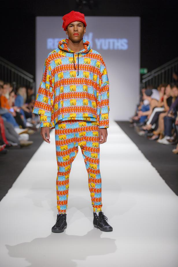 Ein Model präsentiert ein farbenfrohes Outfit auf dem Laufsteg.