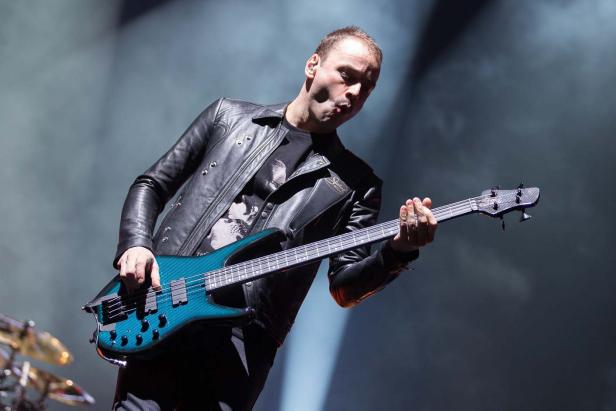 Ein Mann mit Lederjacke spielt auf einer blaugrünen E-Gitarre.