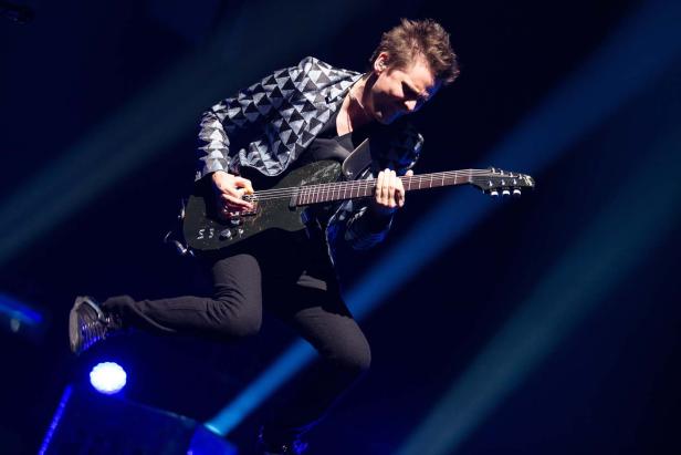 Ein Gitarrist springt auf der Bühne, während er ein Solo spielt.