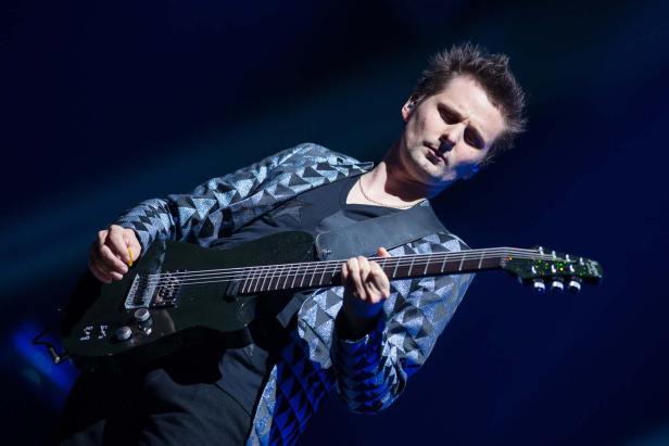 Matthew Bellamy von Muse spielt Gitarre auf der Bühne.