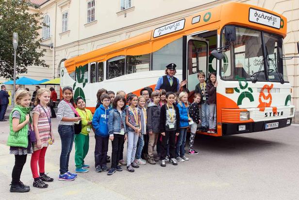 Eine Gruppe Kinder steht vor dem „Dschungel Bus“ mit einem Busfahrer.