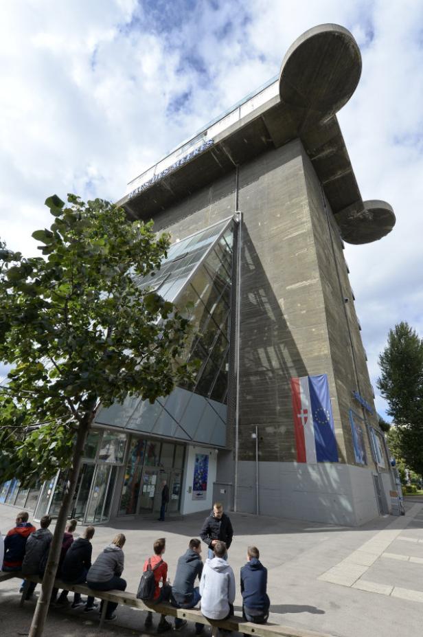 Eine Gruppe von Menschen sitzt vor dem Hamburger Flakturm IV, der heute ein Kulturzentrum beherbergt.