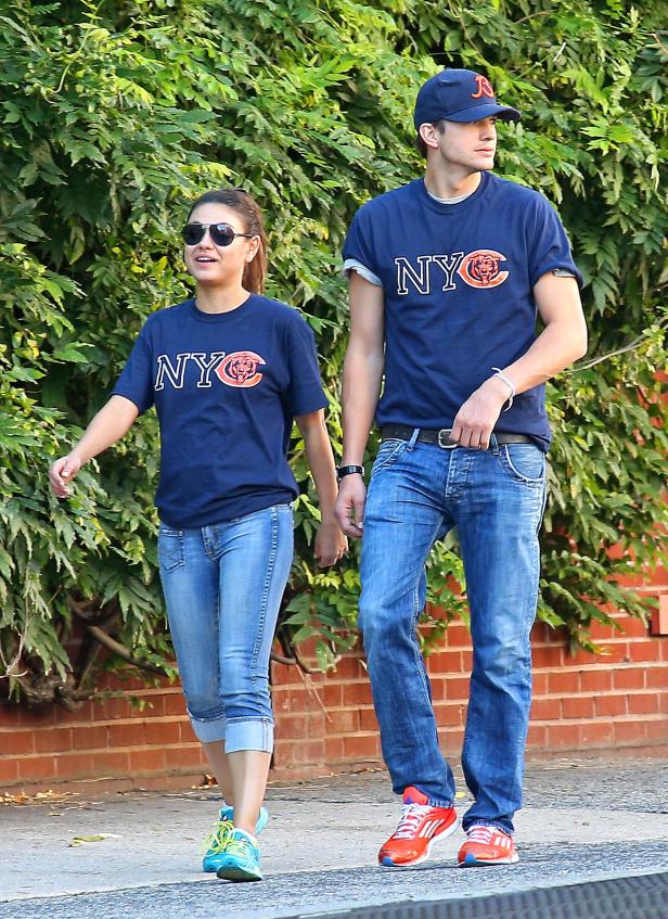 Mila Kunis und Ashton Kutcher spazieren Händchen haltend in passenden T-Shirts.